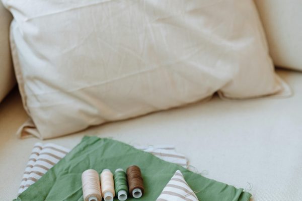 A detailed view of sewing supplies including fabric, threads, and scissors on a cushion. Une vue détaillée des fournitures de couture comprenant du tissu, des fils et des ciseaux sur un coussin.