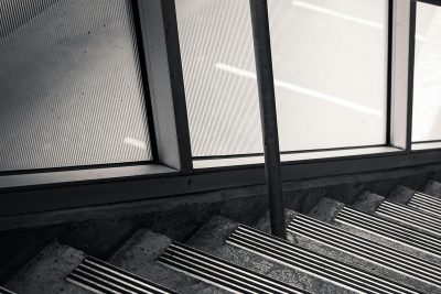 Monochrome image of a staircase with anti-slip strips and handrail, providing safety. Image en noir et blanc d'un escalier avec des bandes antidérapantes et une rampe, offrant de la sécurité.