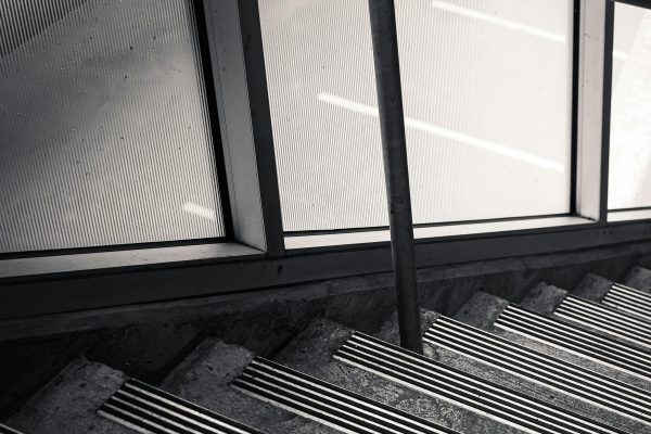 Monochrome image of a staircase with anti-slip strips and handrail, providing safety. Image en noir et blanc d'un escalier avec des bandes antidérapantes et une rampe, offrant de la sécurité.