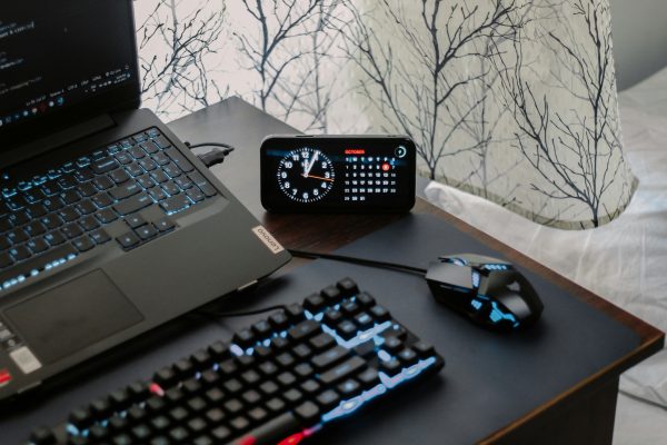 A modern workspace featuring a laptop, digital clock, gaming mouse, and keyboard, ideal for work and tech enthusiasts. Un espace de travail moderne mettant en vedette un ordinateur portable, une horloge numérique, une souris de jeu et un clavier, idéal pour les amateurs de travail et de technologie.