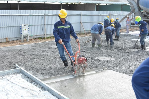 Team of workers smoothing and leveling wet concrete at a construction site. Équipe d'ouvriers lissant et nivelant le béton humide sur un chantier de construction.