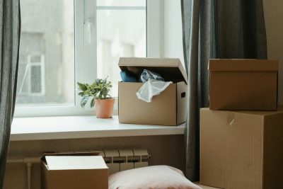 Stack of moving boxes in a sunlit room, symbolizing a fresh start in a new apartment. Pile de cartons de déménagement dans une pièce ensoleillée, symbolisant un nouveau départ dans un nouvel appartement.