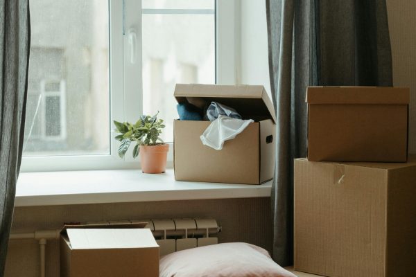 Stack of moving boxes in a sunlit room, symbolizing a fresh start in a new apartment. Pile de cartons de déménagement dans une pièce ensoleillée, symbolisant un nouveau départ dans un nouvel appartement.