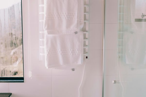 Salle de bain lumineuse et contemporaine dotée d'un porte-serviettes chauffant et d'une douche en verre.