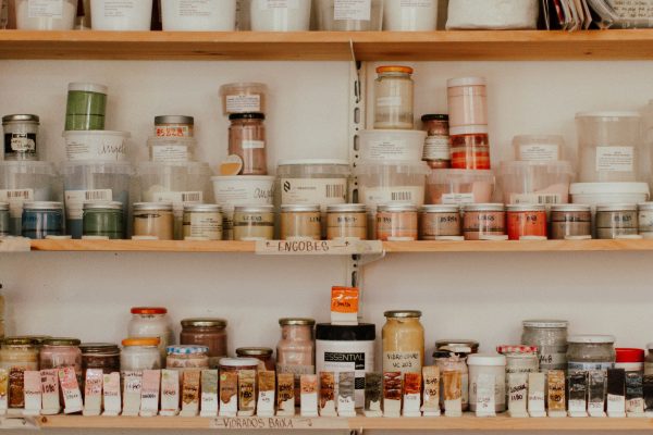 Neatly arranged art supplies on wooden shelves, showcasing a variety of colorful jars and containers. Fournitures artistiques soigneusement arrangées sur des étagères en bois, mettant en avant une variété de pots et contenants colorés.