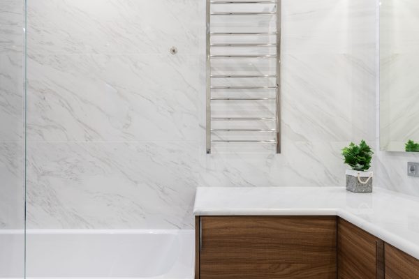 Interior of light modern bathroom with potted green plant on cabinet under mirror on white tile Intérieur d'une salle de bain moderne et lumineuse avec une plante verte en pot sur le meuble sous le miroir sur carrelage blanc