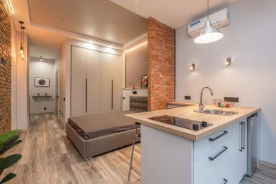 Miniature cuisine avec appareils modernes et chambre à coucher derrière une partition en brique dans un petit appartement style loft