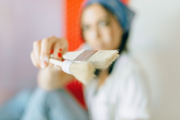 Artistic shot of a woman holding a brush, focusing on creative expression and painting tools. Un plan artistique d'une femme tenant un pinceau, mettant l'accent sur l'expression créative et les outils de peinture.