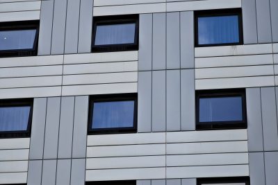 Detailed view of a modern building facade with geometric window patterns. Vue détaillée d'une façade de bâtiment moderne avec des motifs de fenêtres géométriques.