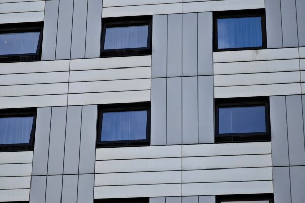 Detailed view of a modern building facade with geometric window patterns. Vue détaillée d'une façade de bâtiment moderne avec des motifs de fenêtres géométriques.