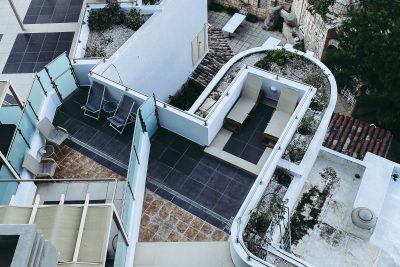 High angle view of a modern multi-level rooftop terrace featuring various seating and lounging areas. Vue de haut d'une terrasse sur le toit moderne à plusieurs niveaux avec diverses zones de repos et de détente.