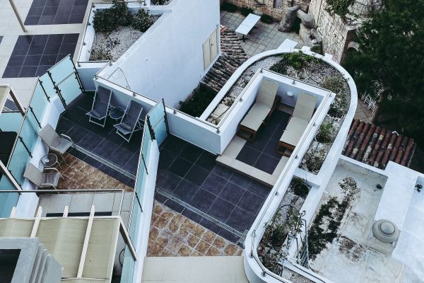 High angle view of a modern multi-level rooftop terrace featuring various seating and lounging areas. Vue de haut d'une terrasse sur le toit moderne à plusieurs niveaux avec diverses zones de repos et de détente.