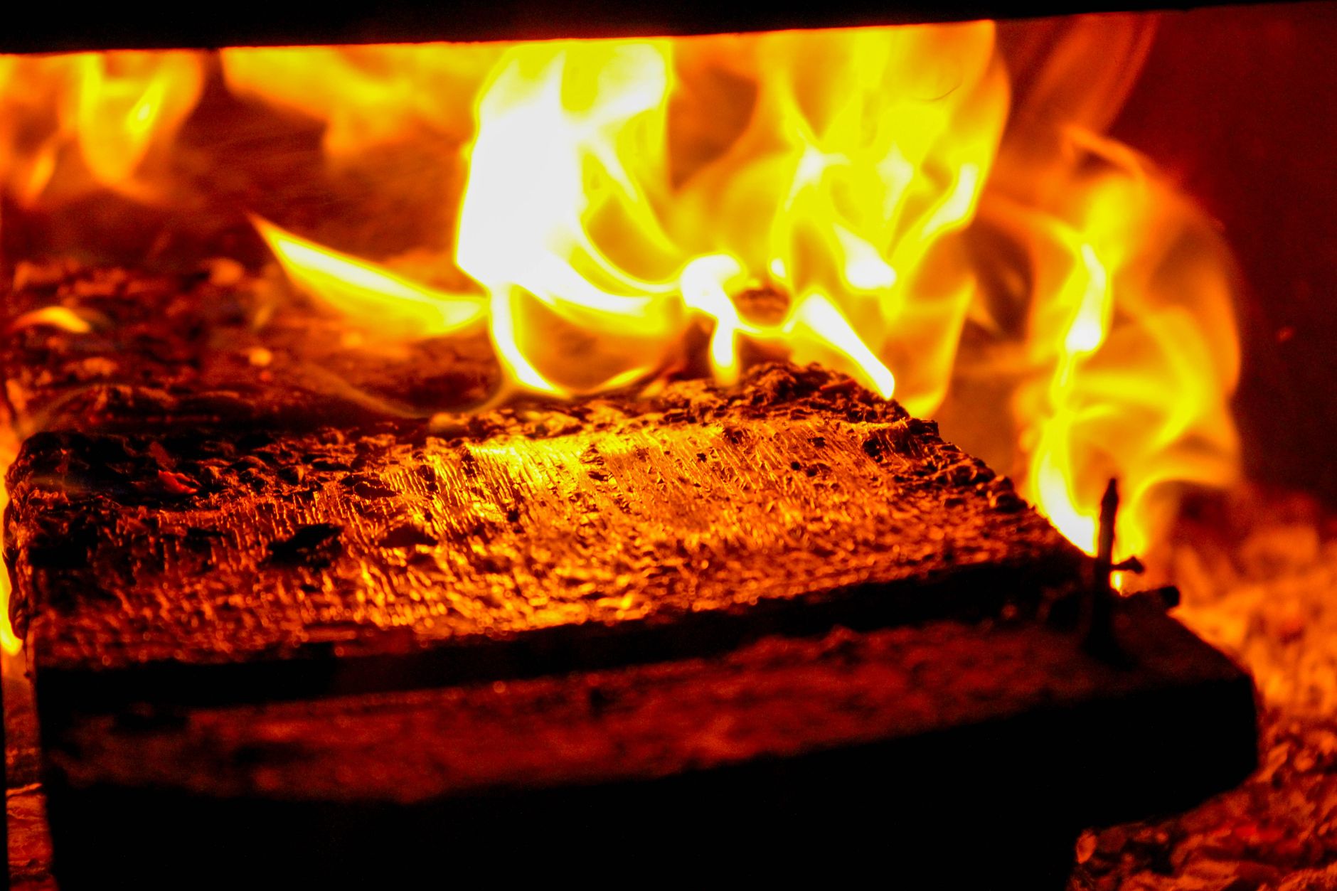 Flammes vives autour d'une bûche dans un foyer fermé