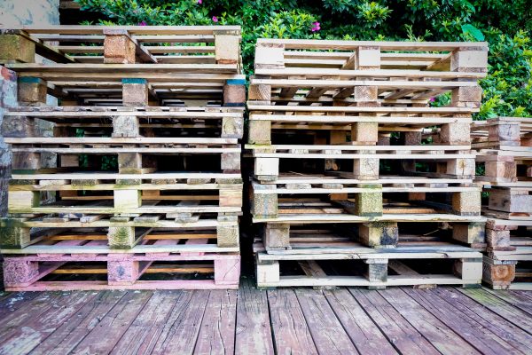 A pile of wooden pallets on a wooden deck surrounded by greenery, suitable for industry and recycling themes. Un tas de palettes en bois sur une terrasse en bois entourée de verdure, adapté aux thèmes de l'industrie et du recyclage.