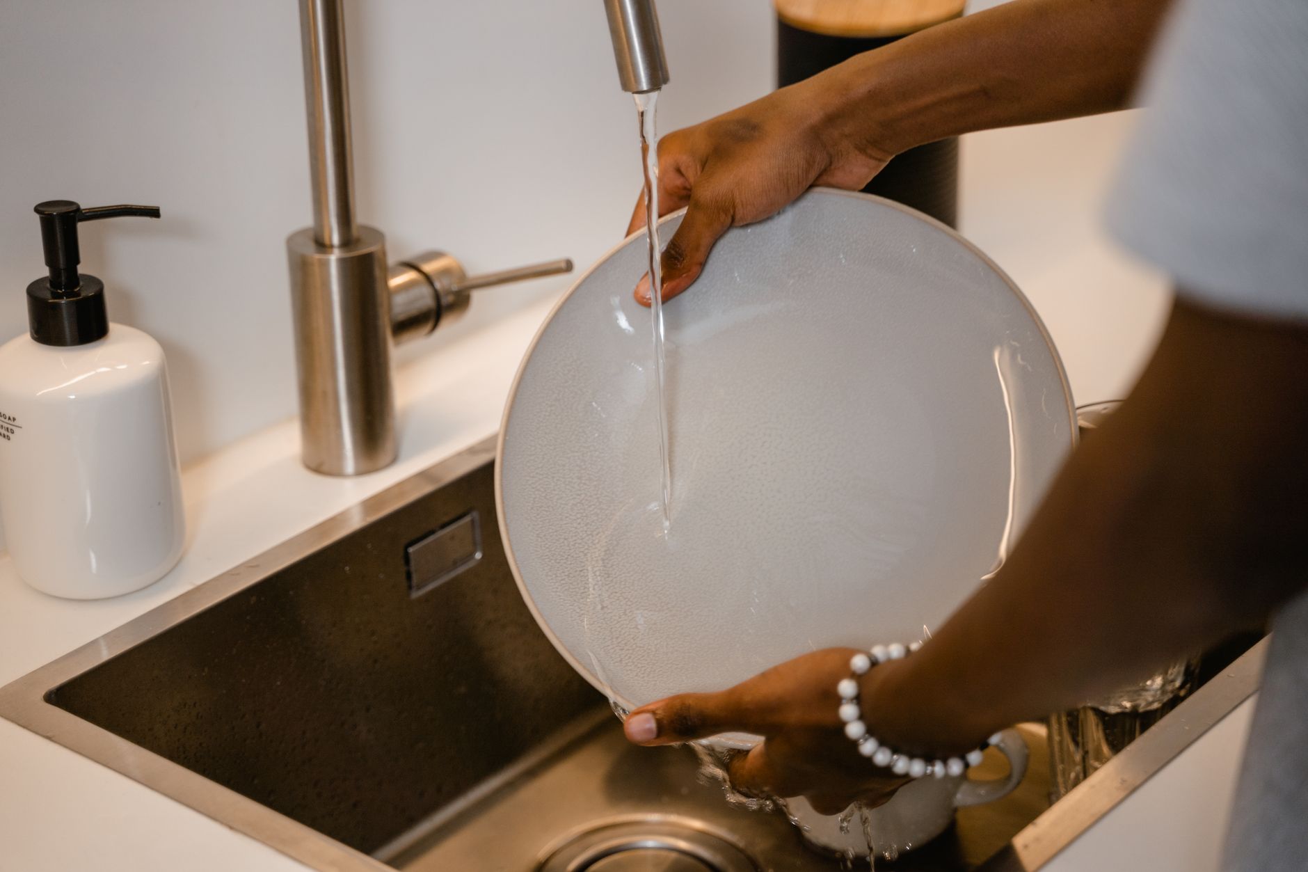 Assiette rincée sous l’eau dans un évier