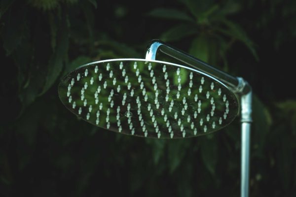 Pommeau de douche chromé au-dessus d’un mur carrelé